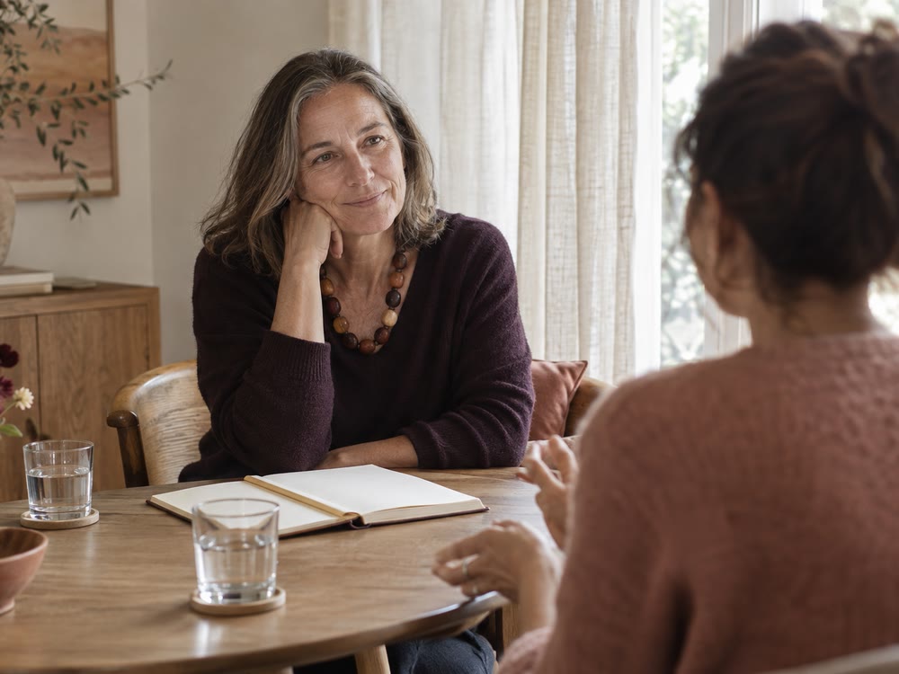 A consultant listening across a small table with an open notebook